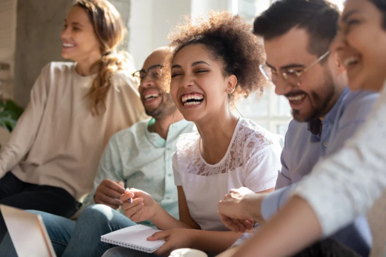 A small group of people laughing together during a therapy session, representing the supportive community found in rehab programs.