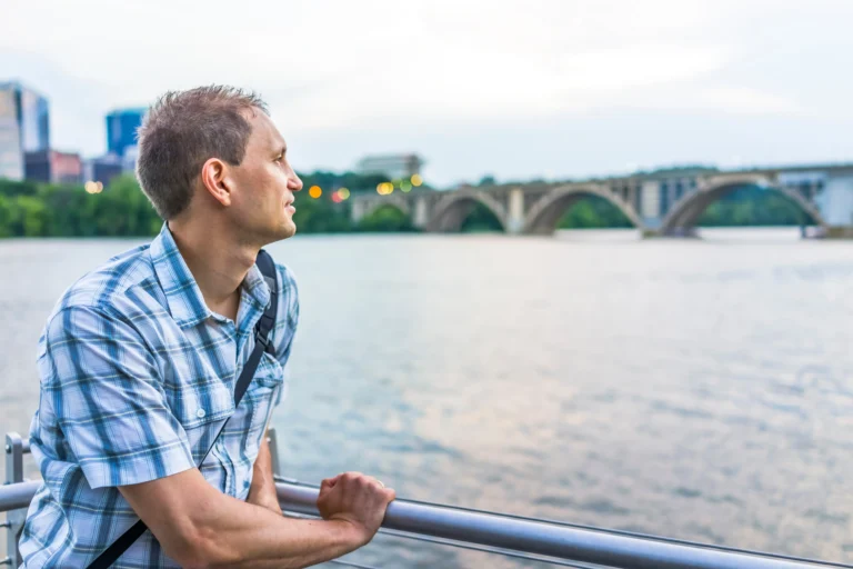 Man looking over a waterfront near a bridge in Virginia, representing recovery after inpatient detox and rehab.