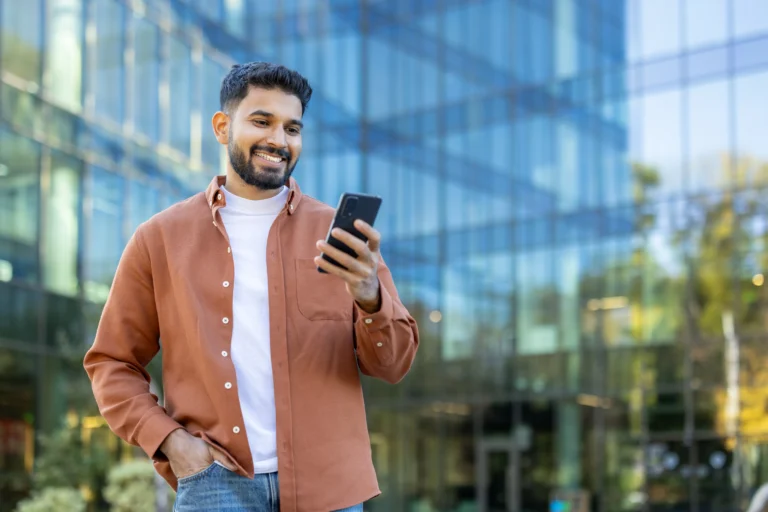 Man using his phone outside a modern building, reflecting the first call to begin same-day rehab admission in Northern Virginia.